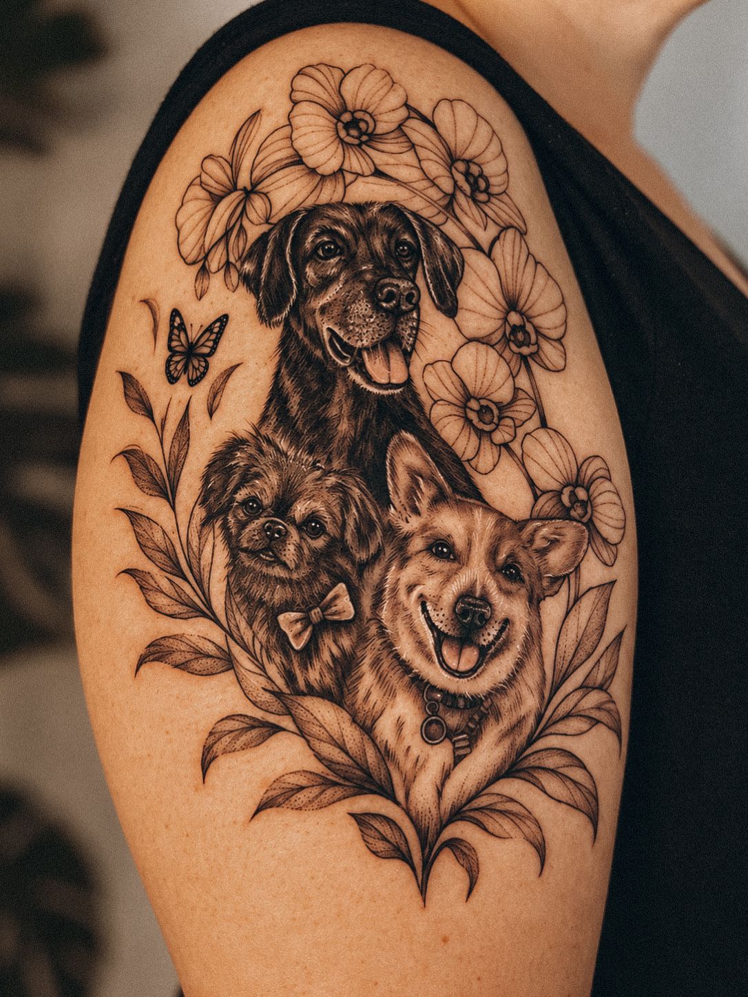 Black and grey portrait of three dogs framed by flowers on the upper arm