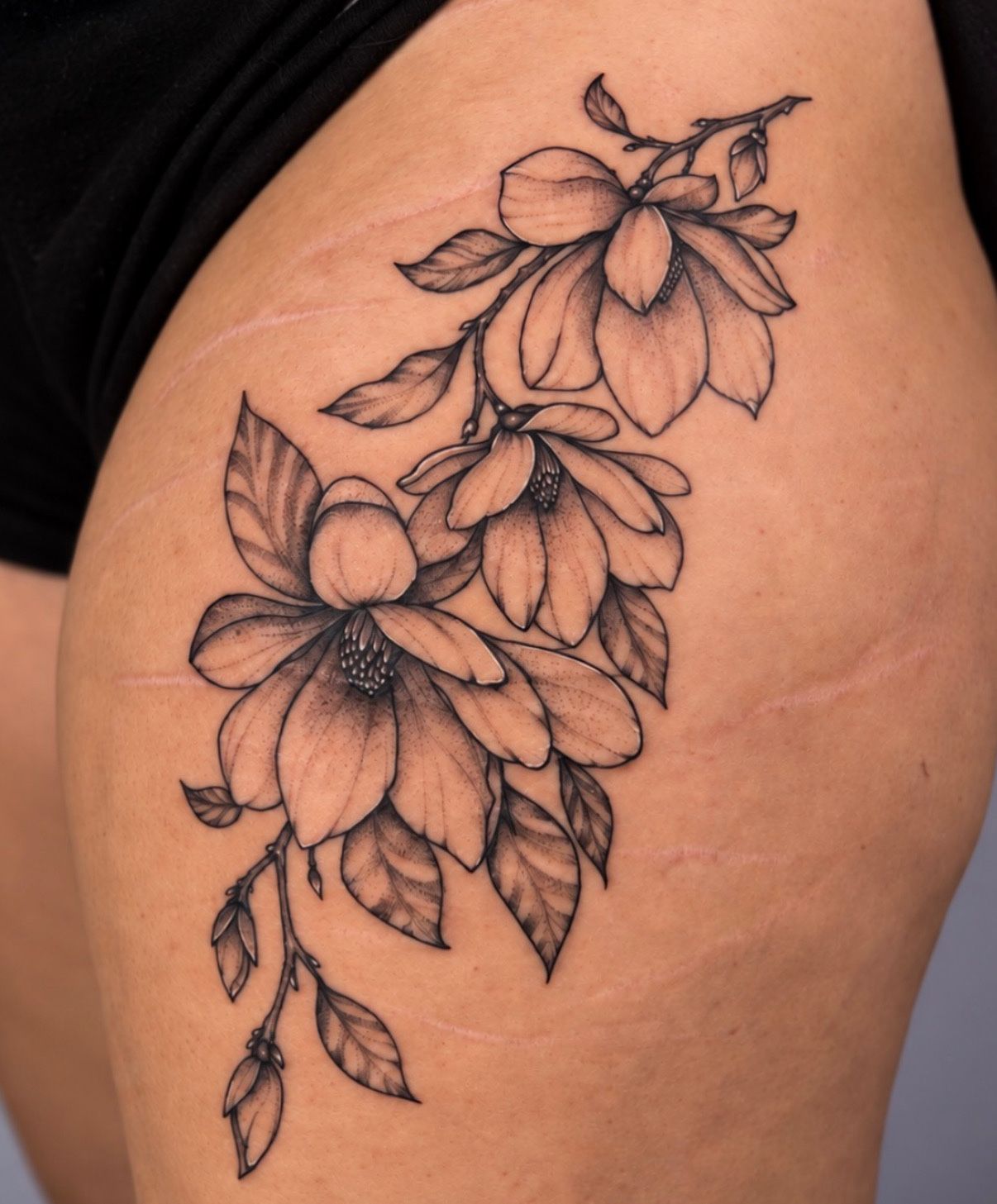 Black and grey magnolia branch on the thigh